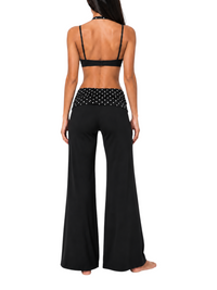 Back view of a model wearing the Ninety Nine Polka Noir set, featuring a black sports bra and wide-leg yoga pants.