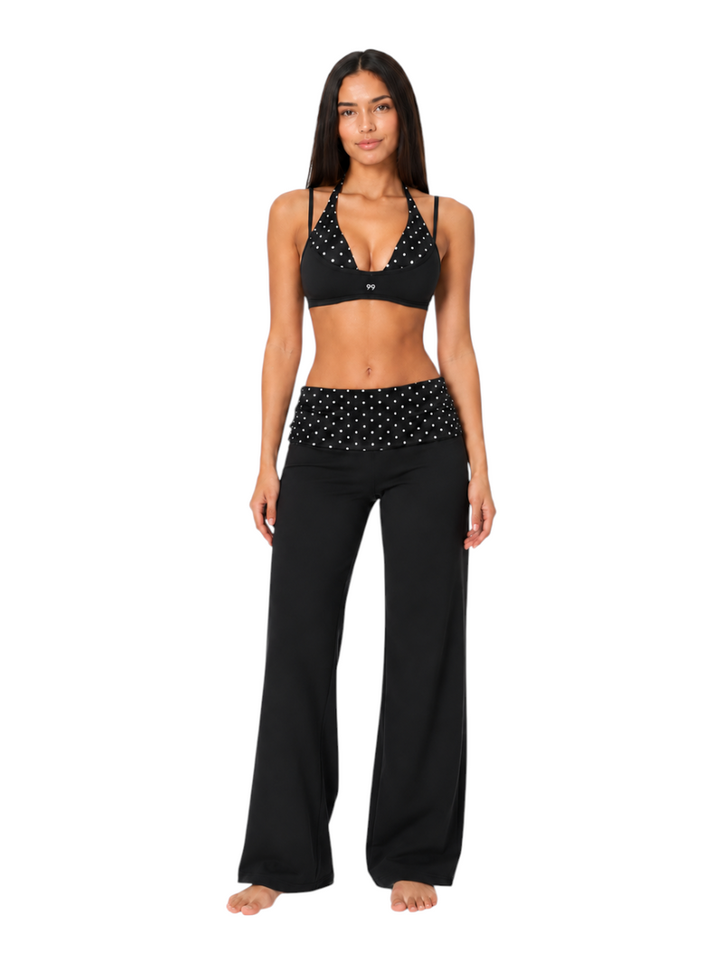Ninety Nine Polka Noir set featuring a black polka dot halter sports bra and matching high-waist flared yoga pants.
