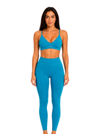 Model wearing a Ninety Nine Aqua Muse set featuring a bright aqua blue V-neck crop top and matching high-waisted leggings