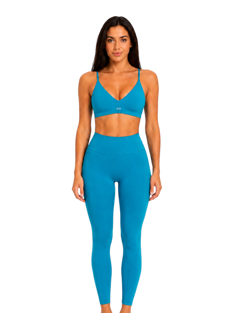 Model wearing a Ninety Nine Aqua Muse set featuring a bright aqua blue V-neck crop top and matching high-waisted leggings