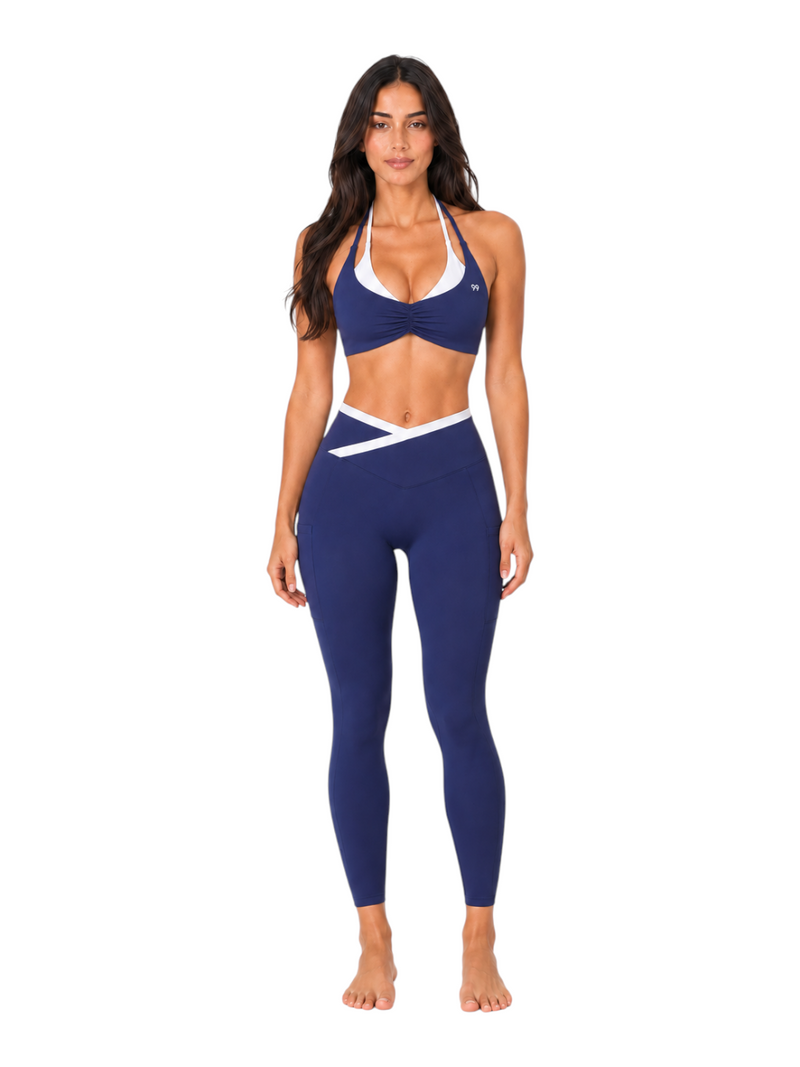 Model wearing Ninety Nine Ocean Edge Set featuring a navy and white color-blocked halter bra and high-rise leggings.